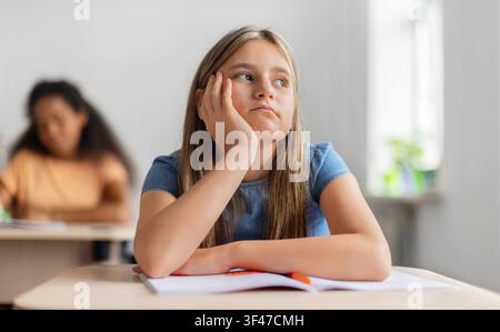 Gelangweilte Schulmädchen ruht ihr Gesicht auf der Hand und schaut während des Unterrichts weg Stockfoto