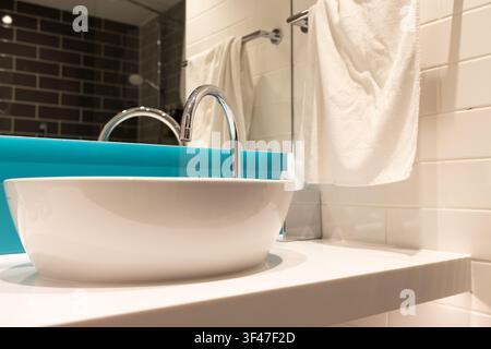 Saubere Handtücher, die an einem Waschbecken in einem modernen Badezimmer mit blauen Akzenten und einem Spiegel hängen Stockfoto