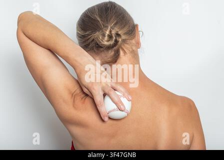 Rückansicht einer Frau, die einen Ball zur Selbstmassage von Nacken und Schulterblättern verwendet, Muskelverspannungslinderungstechnik. Isoliert auf neutralem Hintergrund. Stockfoto