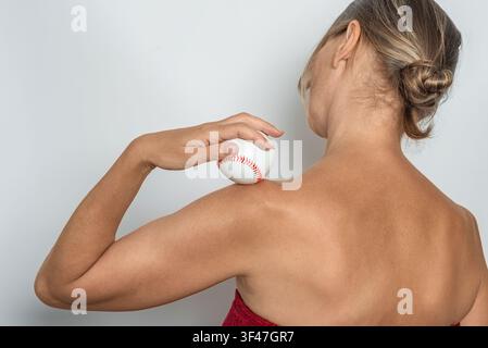 Rückansicht einer Frau, die einen Ball zur Selbstmassage der Schulter verwendet, Technik zur Linderung von Muskelverspannungen. Isoliert auf neutralem Hintergrund. Stockfoto