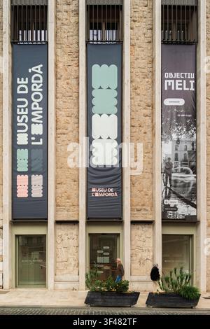 Fassade des Museu de l'Empordà in Figueres, Girona, Spanien, mit großen vertikalen Bannern, Steinreliefs und Menschen, die am Eingang vorbeigehen. Stockfoto