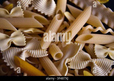 Nahaufnahme verschiedener Arten von frischer Rohpasta auf schwarzem Hintergrund Stockfoto
