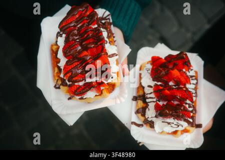 Verlockende belgische Waffeln mit frischen Erdbeeren, Schlagsahne und Schokoladensoße belegt. In Brüssel aufgenommen, zeigt ein beliebtes Straßenessen Stockfoto