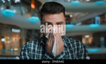 Gesundheitsgefährdeter kaukasischer Mann, der vor saisonaler Allergie niest, mit laufender Nase, Grippekrankheit, Kunde, Mann, niest, wischt sich die Nase mit einer Papierserviette ab, Geschäftsmann Stockfoto