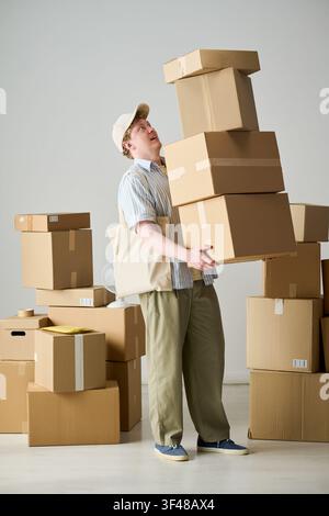 Erwachsener Mann trägt gestapelte Versandkartons für den Umzugsservice Stockfoto