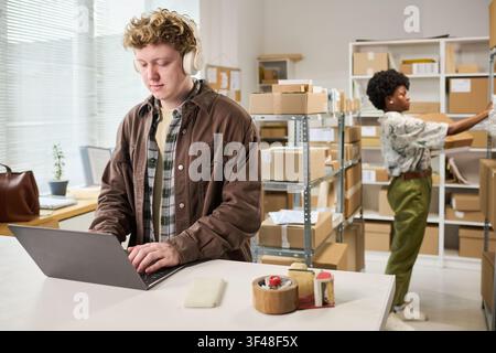 Erwachsener Mann verwaltet Online-Bestellungen in einem kleinen Büro für die Erfüllung von Bestellungen Stockfoto