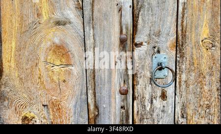 Nahaufnahme einer rustikalen verwitterten Holztür mit antiker Eisentürschließe in der Schweiz Stockfoto