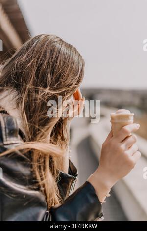 Eisdame Haar junge Frau mit wallendem Haar hält eine erfrischende Eiswaffel und genießt einen sonnigen Tag im Freien Stockfoto