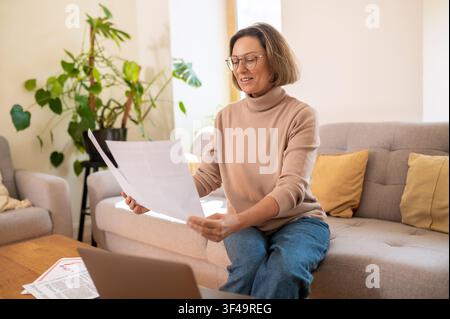 Lächelnde Geschäftsfrau mittleren Alters liest eine Finanzzeitung Stockfoto