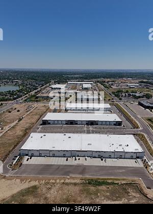 Luftbild von modernen Industrie-Lagerhallen und Vertriebszentren mit großen weißen Dächern, weitläufigen Parkplätzen und umgebender urbaner Infrastruktur Stockfoto