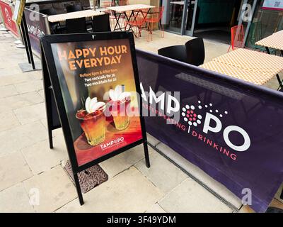 Manchester, UK - 10. Mai 2026: Ein Sandwich-Brett wirbt für Happy-Hour-Cocktails und Mocktails vor einem lässigen Tampopo-Restaurant mit Terrassensitzen Stockfoto