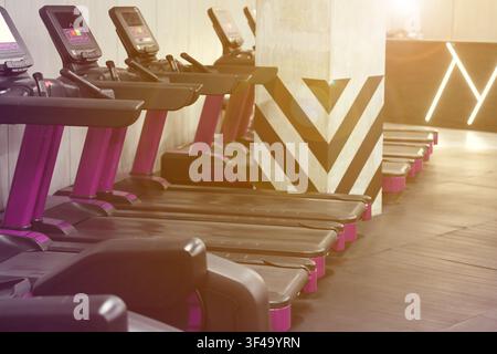 Cardio-Zone mit Laufbändern in einem sonnendurchfluteten Fitnessstudio, selektive Schärfe Stockfoto