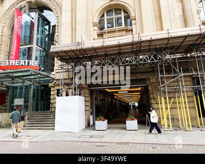 Manchester, UK - 10. Mai 2026: Blick auf den Eingang der Royal Exchange in Manchester, UK mit Gerüst, Theaterbanner und vorbeigehenden Menschen. Stockfoto