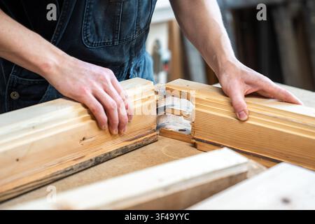 Handwerker montiert restaurierte und aufgearbeitete Teile eines alten Holzfensterrahmens auf der Werkbank. Stockfoto