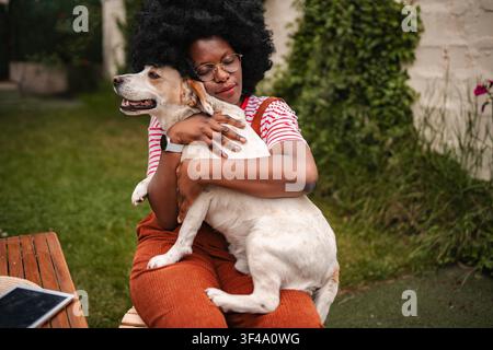 Erwachsene Frau umarmt einen Hund und genießt die Zeit im Hinterhof Stockfoto