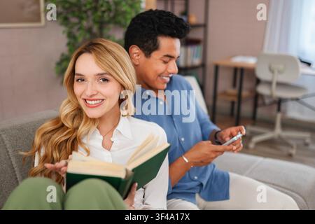 Zufriedenes, vielfältiges Paar entspannt sich auf dem Sofa zu Hause Stockfoto