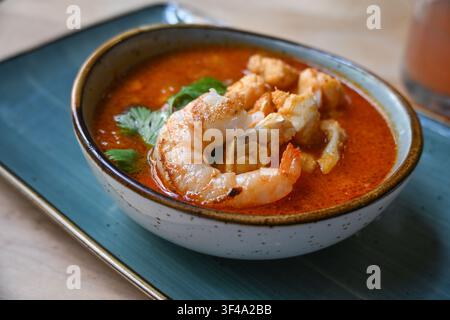 Garnelen- und Fischsuppe in Tomatensauce, garniert mit Petersilie, serviert in einer Schüssel, köstliche Meeresfrüchte, selektiver Fokus, geringe Tiefenschärfe Stockfoto