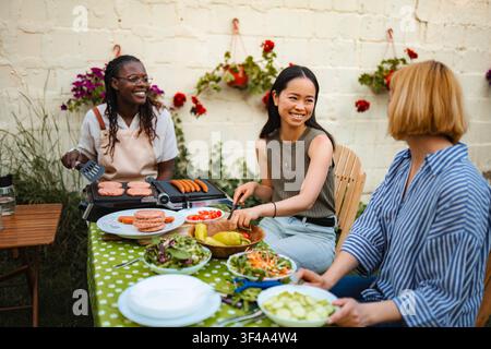 Multiethnische Frauenfreunde genießen Grillen im Hinterhof und unterhalten sich Stockfoto