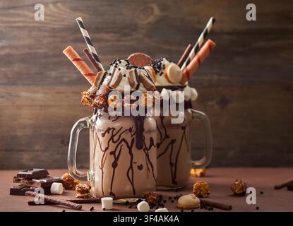 Schokoladenmilchshake mit Eis und Schlagsahne, Marshmallow, süßem Popcorn, Keksen, Waffeln, serviert in einem Glasmason-Glas. Stockfoto