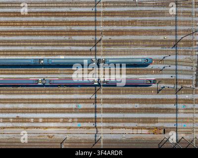 Luftbild des Bahnhofs Daniken mit zwei Personenzügen, die auf parallelen Gleisen in Daniken, Solothurn, Schweiz, abgestellt sind. Stockfoto