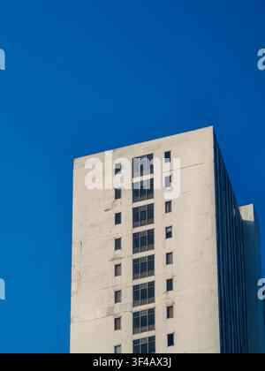 Hohe weiße Gebäudefassade mit Reihen von Fenstern vor einem klaren blauen Himmel Stockfoto