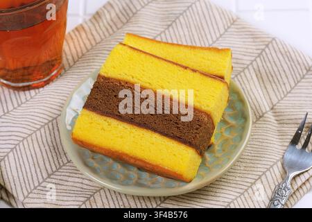 Traditioneller indonesischer Spiku-Kuchen oder Kue Lapis Surabaya, serviert mit Tee auf weißem Tisch, repräsentiert Komfortessen, Frühstück und Snackzeit-Konzept. Stockfoto