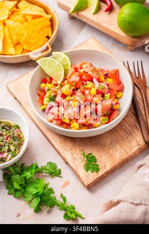 Frisch zubereiteter Pico de Gallo mit Mais und Limettenspaltern, serviert mit Tortillachips Stockfoto