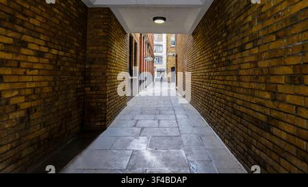 London - 07 21 2022: Schmale Ziegelpassage am Banbury Court mit Steinpflaster und Tiefenperspektive. Schmaler Durchgang zwischen Ziegelfassaden mit gelbem-b Stockfoto
