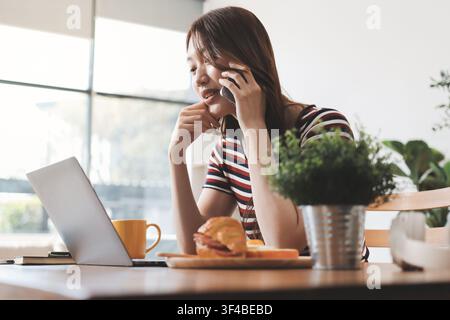 Glück Unternehmer schönes Geschäft asiatische junge Frau tragen lässig Handy zum Einkaufen online genießen Sie mit sozialen Medien und Laptop zu Hause Stockfoto