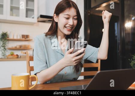 Glück Unternehmer schönes Geschäft asiatische junge Frau tragen lässig Handy zum Einkaufen online genießen Sie mit sozialen Medien und Laptop zu Hause Stockfoto