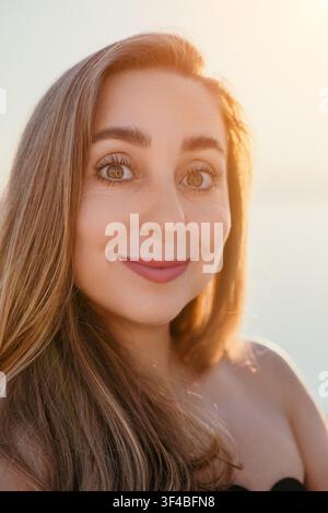 Frauenporträt Sonnenuntergang Nahaufnahme eines lächelnden jungen Frau im Freien während der goldenen Stunde, die warmes Sonnenlicht und eine friedliche Atmosphäre genießt Stockfoto
