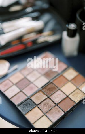 Lidschatten-Palette Auf Kosmetiktisch, Verschiedene Matte- Und Schimmerschalen, Weiche Borstenpinsel, Foundation-Flasche, Warmes Natürliches Licht, Flach Stockfoto