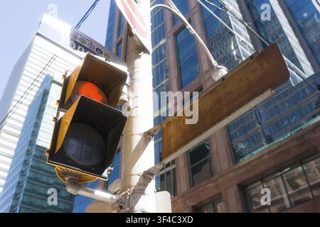 Schräger Ampelschirm und leere Straßenecke unter einem Glas-Wolkenkratzer, der einen Kontrast zwischen verwittertem Metall und polierter Fassade erzeugt, Nahaufnahme Stockfoto