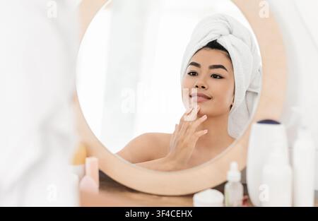 Schöne asiatische junge Frau Anwendung Gesichtscreme Stockfoto