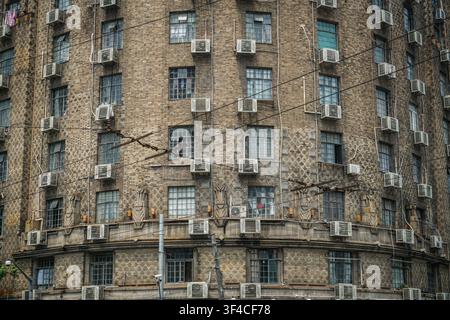 Die Ecke und zwei Seiten eines alten, mehrstöckigen Art-Deco-Gebäudes sind sichtbar, das aus dunkelbraunen und beigen Ziegeln mit einem Diamantmuster konstruiert ist, fea Stockfoto