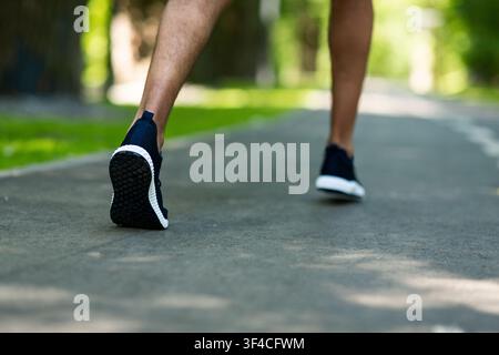 Beschnittene Ansicht des schwarzen Läufers auf der Joggingstrecke im Park, Nahaufnahme der Beine Stockfoto