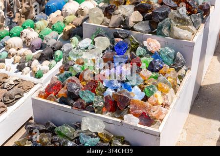 Sammlung von lebendigen recycelten Glasfragmenten und detaillierten Tierfiguren, die an einem Marktstand im Freien ausgestellt sind und Souvenirs anbieten Stockfoto