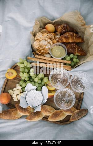 Genießt ein köstliches Picknick mit Früchten, Gebäck und Käse an einem warmen Sommernachmittag Stockfoto