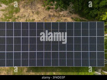 Luftaufnahme einer großen Fläche von Solarmodulen, die auf dem Boden installiert sind, umgeben von grünem Gras und Vegetation in Bacalar, Quintana Roo, Mexiko. Stockfoto