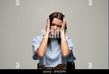 Gestresste junge Frau leidet unter Kopfschmerzen oder Migräne, verspürt schmerzhaften Druck und geistige Belastung Stockfoto