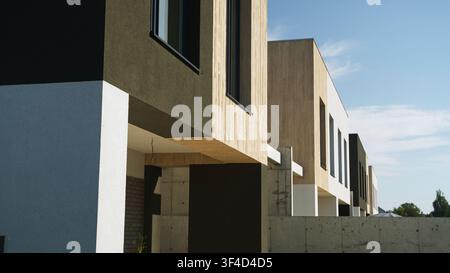 Moderne Reihenhäuser mit minimalistischer Architektur und kontrastierenden Fassaden, die Reihen von Neubauwohnungen im Vorort schaffen Stockfoto