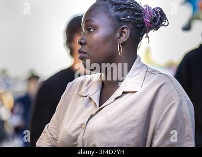 Dijon Burgund Frankreich 9. Mai 2026. Halbporträt einer attraktiven schwarzen Frau mit geflochtenen Haaren, die vor bunten Ständen auf einem Jahrmarkt steht. Stockfoto