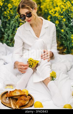 Entspannung in einem Feld gelber Blumen mit einem Frühstücksbuffet an einem sonnigen Tag Stockfoto
