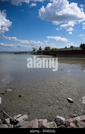 Historisches hölzernes Szigetfurdo-Bad an der Uferpromenade des Balaton-Sees mit niedrigem Wasserstand und freiliegender Schlammlandschaft an einem sonnigen Tag, Keszthely, Ungarn. Stockfoto