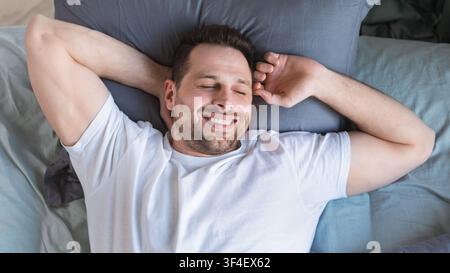 Guy Waking Stretching Hände Liegen Im Bett, Blick Von Oben Stockfoto