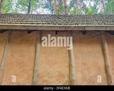 Authentische ländliche Architektur, die Flechtwerk- und Lehmbautechnik mit einem rustikalen Ziegeldach zeigt, umgeben von Bäumen Stockfoto