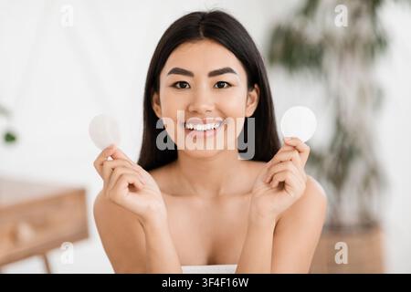 Schöne asiatische Frau mit zwei Wattepads Stockfoto