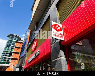 Manchester, UK - 10. Mai 2026: Hellrote HOP-Vietnamesische Straßenessen-Fassade an einem modernen Glas-Einkaufsgebäude in Manchester, UK. Stockfoto