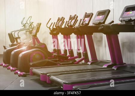 Cardio-Zone mit Fitnessbikes und Laufbändern in einem sonnendurchfluteten Fitnessstudio, selektive Fokussierung Stockfoto