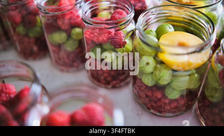 Frische Himbeeren, Stachelbeeren und Aprikosen in Gläsern für Kompott Stockfoto